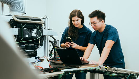 Two people are working together on a laptop in a laboratory.